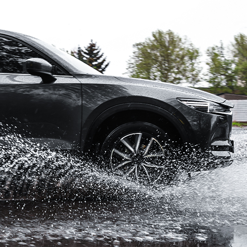 A black vehicle driving through water.