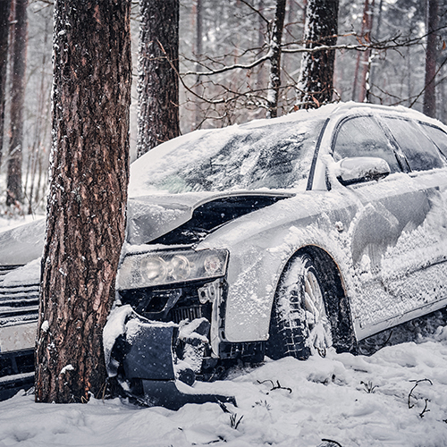 Car crash. A white passenger car ran into a tree in winter conditions. 